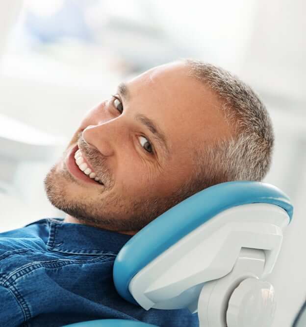 man with denim jacket smiling in exam chair