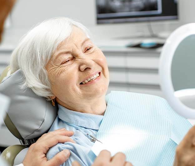 senior woman admiring her new smile in a mirror