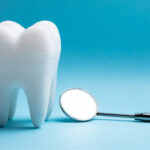Closeup of a tooth extraction next to a special dental mirror on a blue background in Shoreline, WA