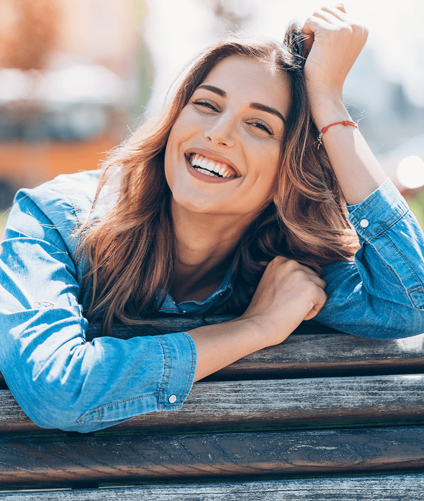 a smiling woman leaning on a fence