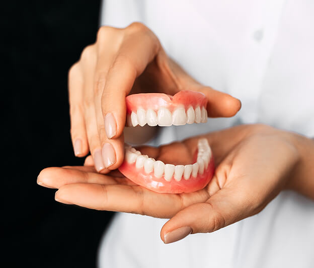 closeup of a person holding a set of dentures