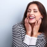 Brunette woman in a striped shirt smiles happily after professional teeth whitening in Shoreline, WA
