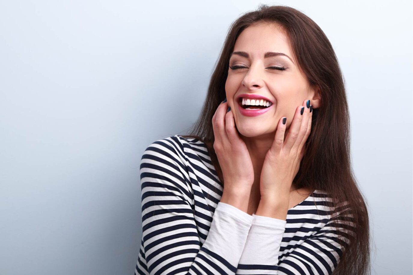 Brunette woman in a striped shirt smiles happily after professional teeth whitening in Shoreline, WA