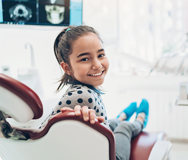 young, smiling girl sitting in a dental chair