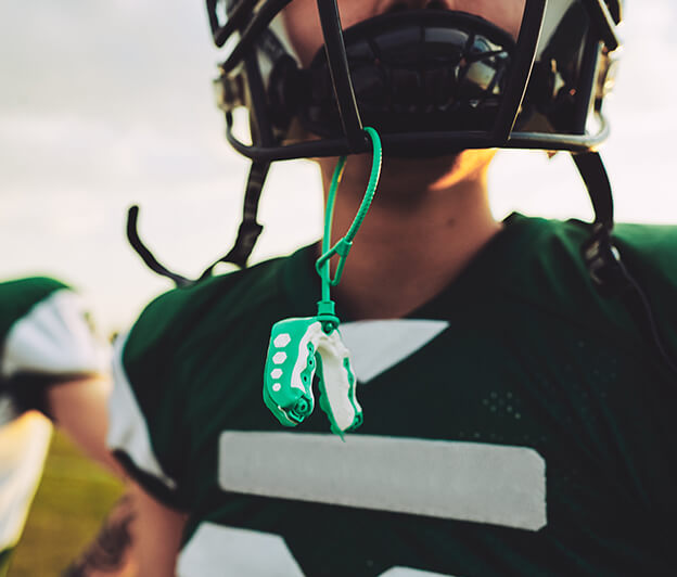 closeup of a youth football player's mouthguard hanging from his helmet